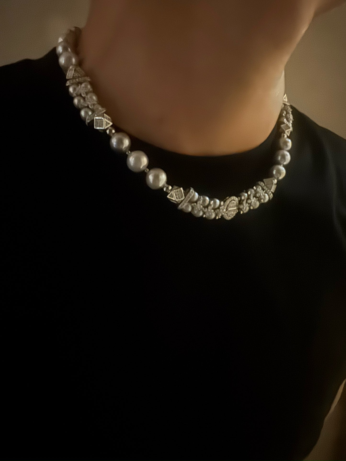 Pearl necklace worn by a person on a plain background