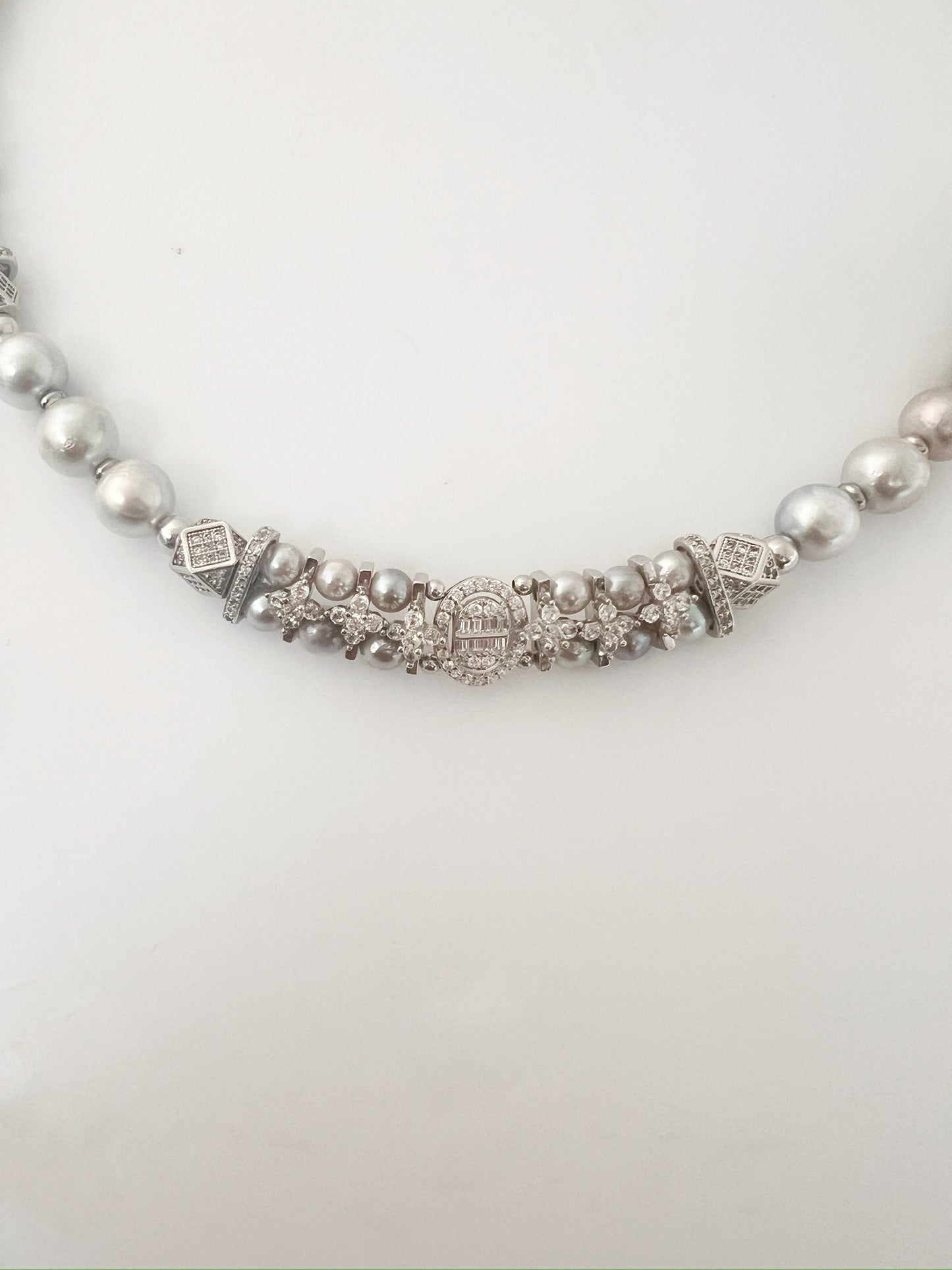 Pearl necklace with decorative clasp on a white background