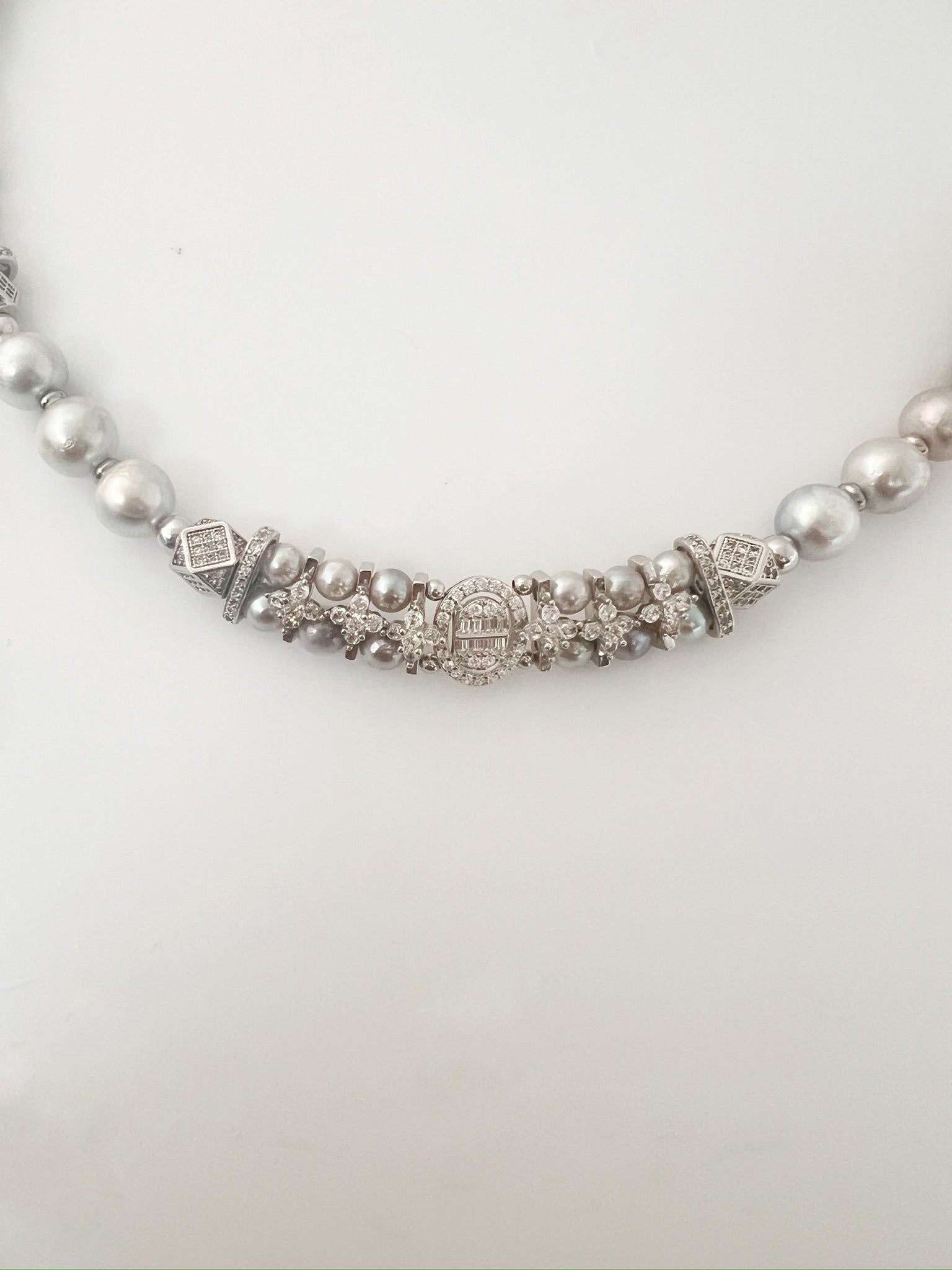 Pearl necklace with decorative clasp on a white background