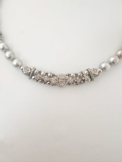 Pearl necklace with decorative clasp on a white background