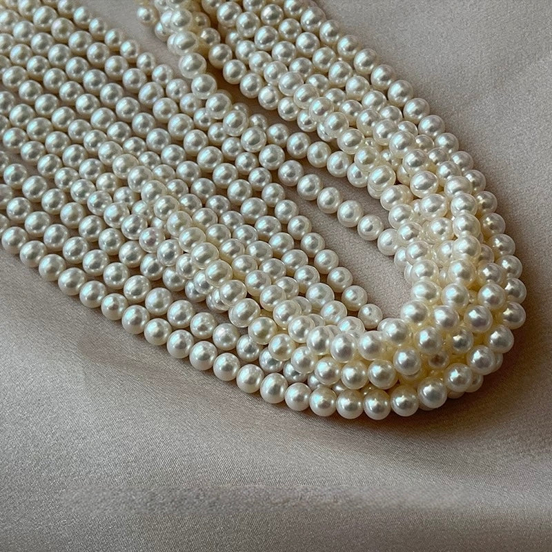 White Pearl Necklace displayed elegantly on a soft fabric background, showcasing multiple strands of lustrous pearls.