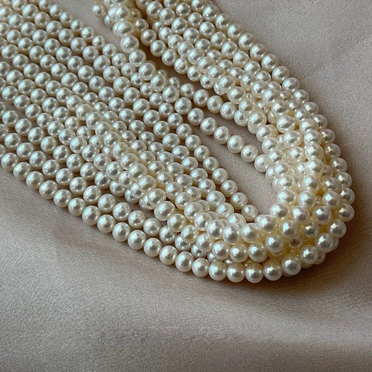 White Pearl Necklace displayed elegantly on a soft fabric background, showcasing multiple strands of lustrous pearls.