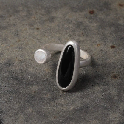 Silver ring with a black stone on a textured gray surface
