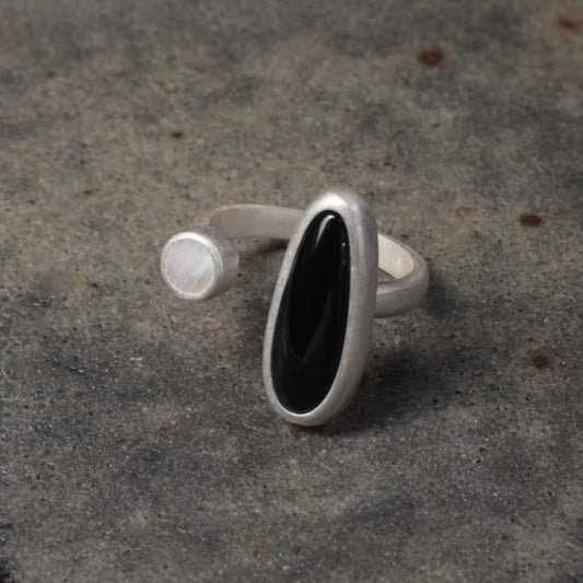 Silver ring with a black stone on a textured gray surface
