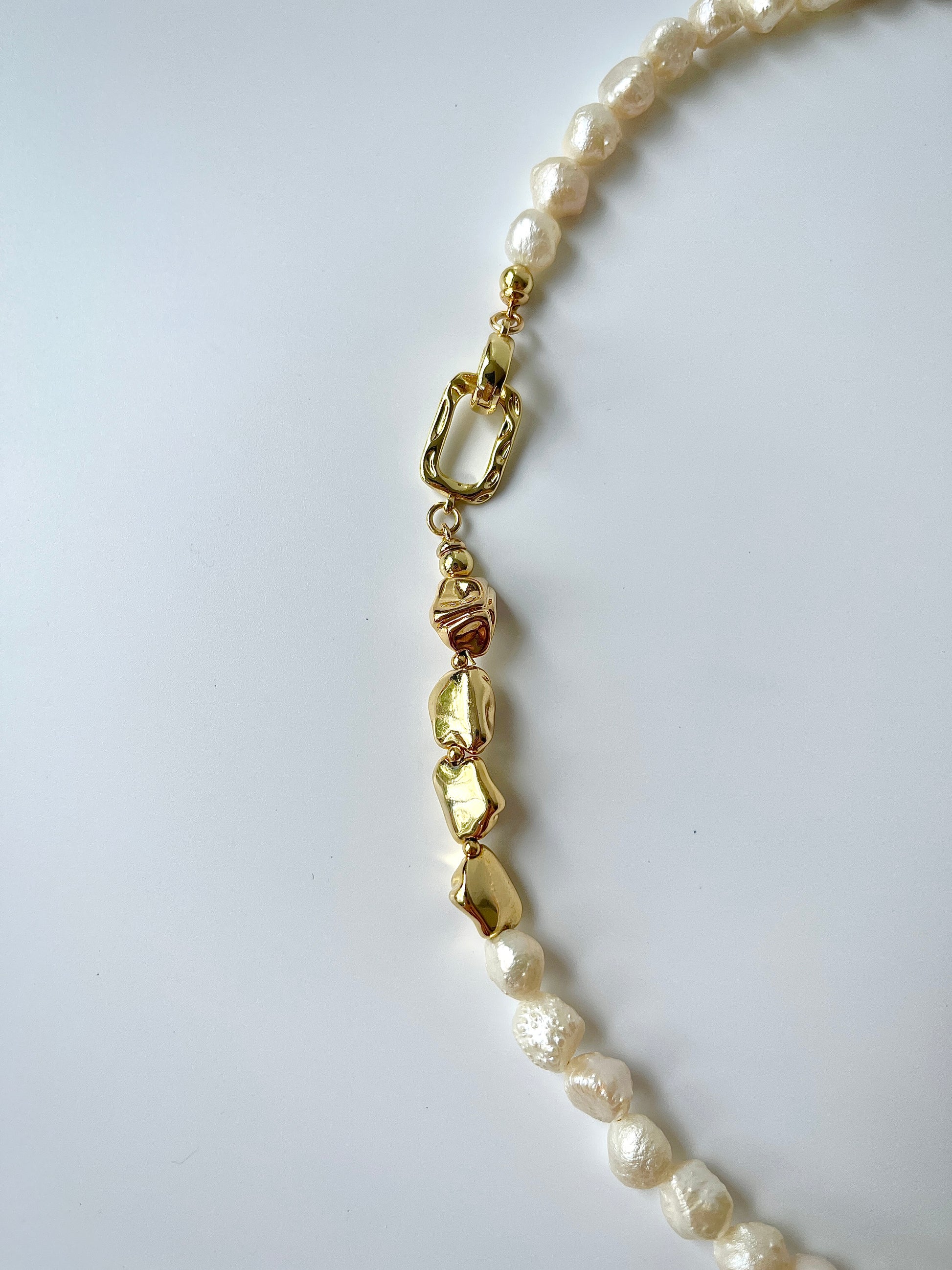 Pearl necklace with gold accents on a white background