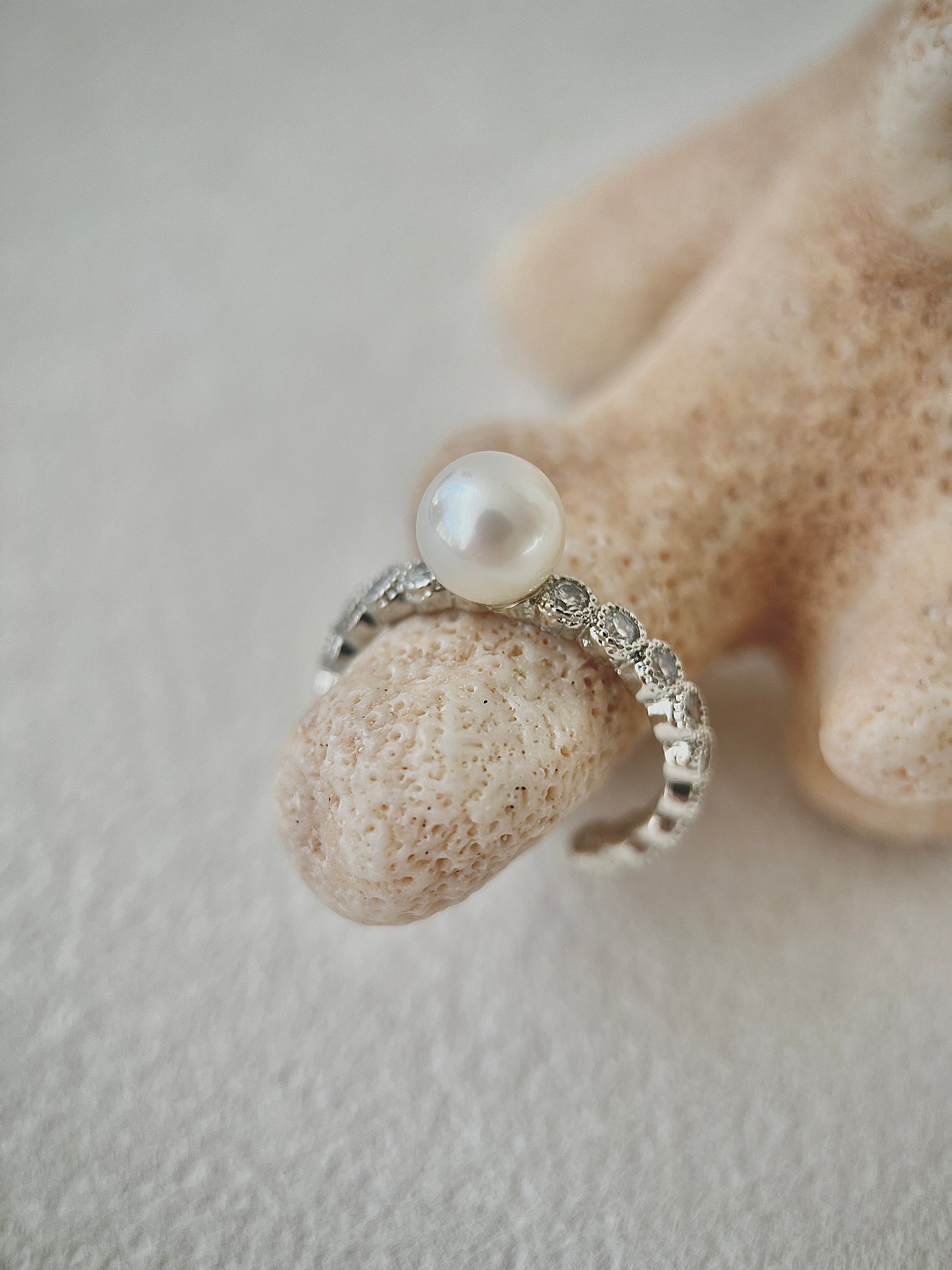 Silver ring with a pearl on a textured surface