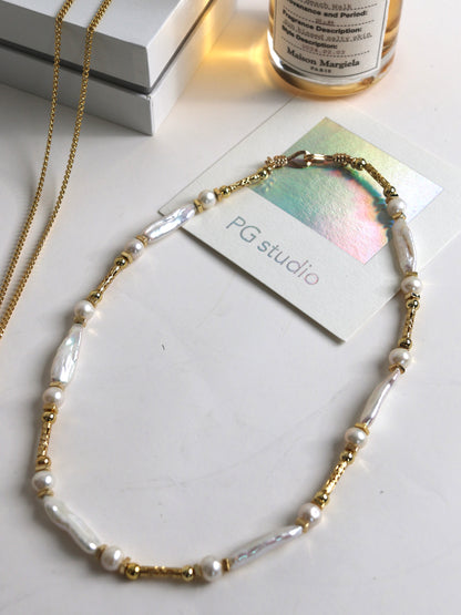 Pearl necklace for men with gold accents on a white surface with 'PG studio' card.