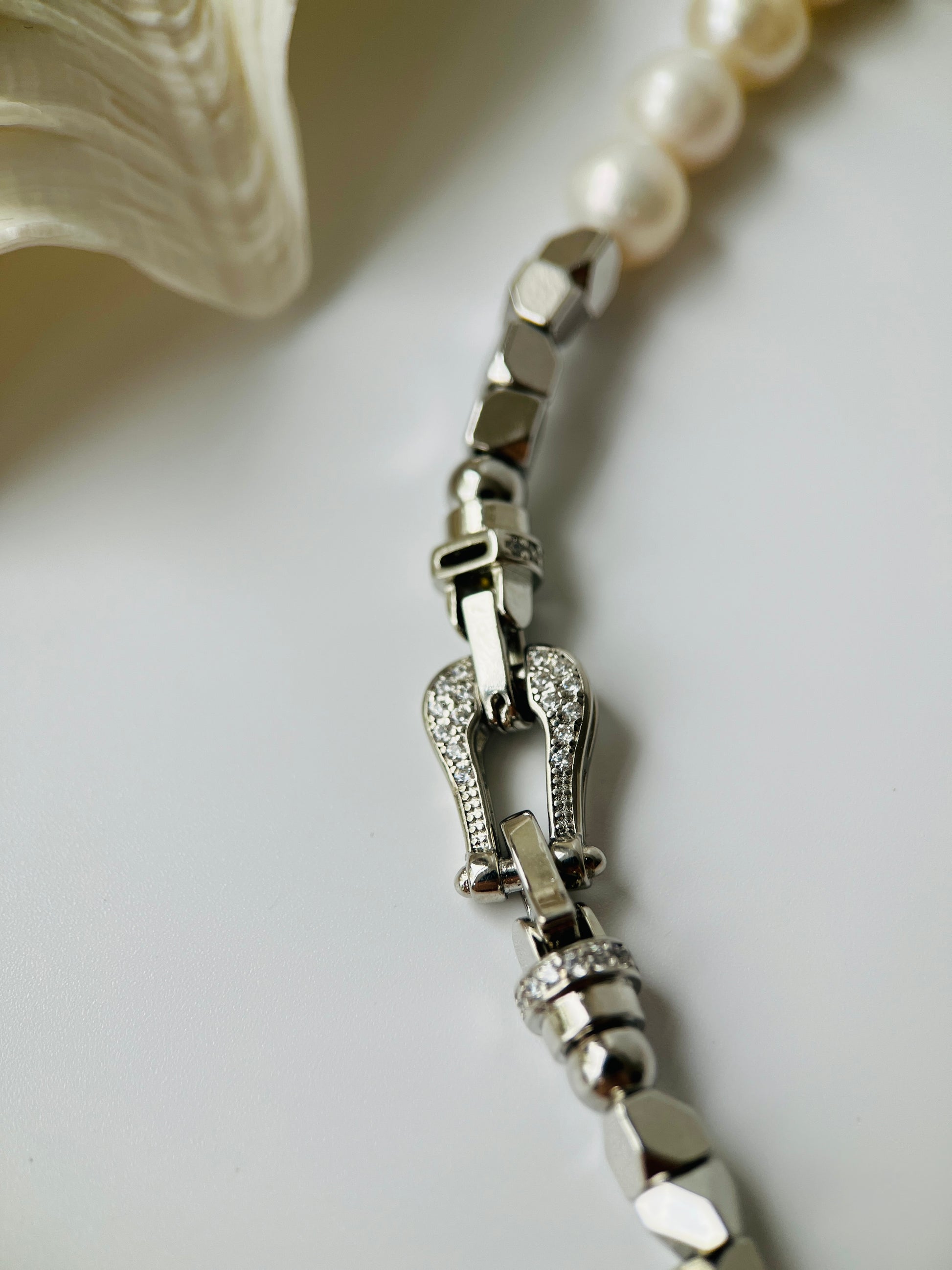 Silver pearl necklace with diamond accents on a light background