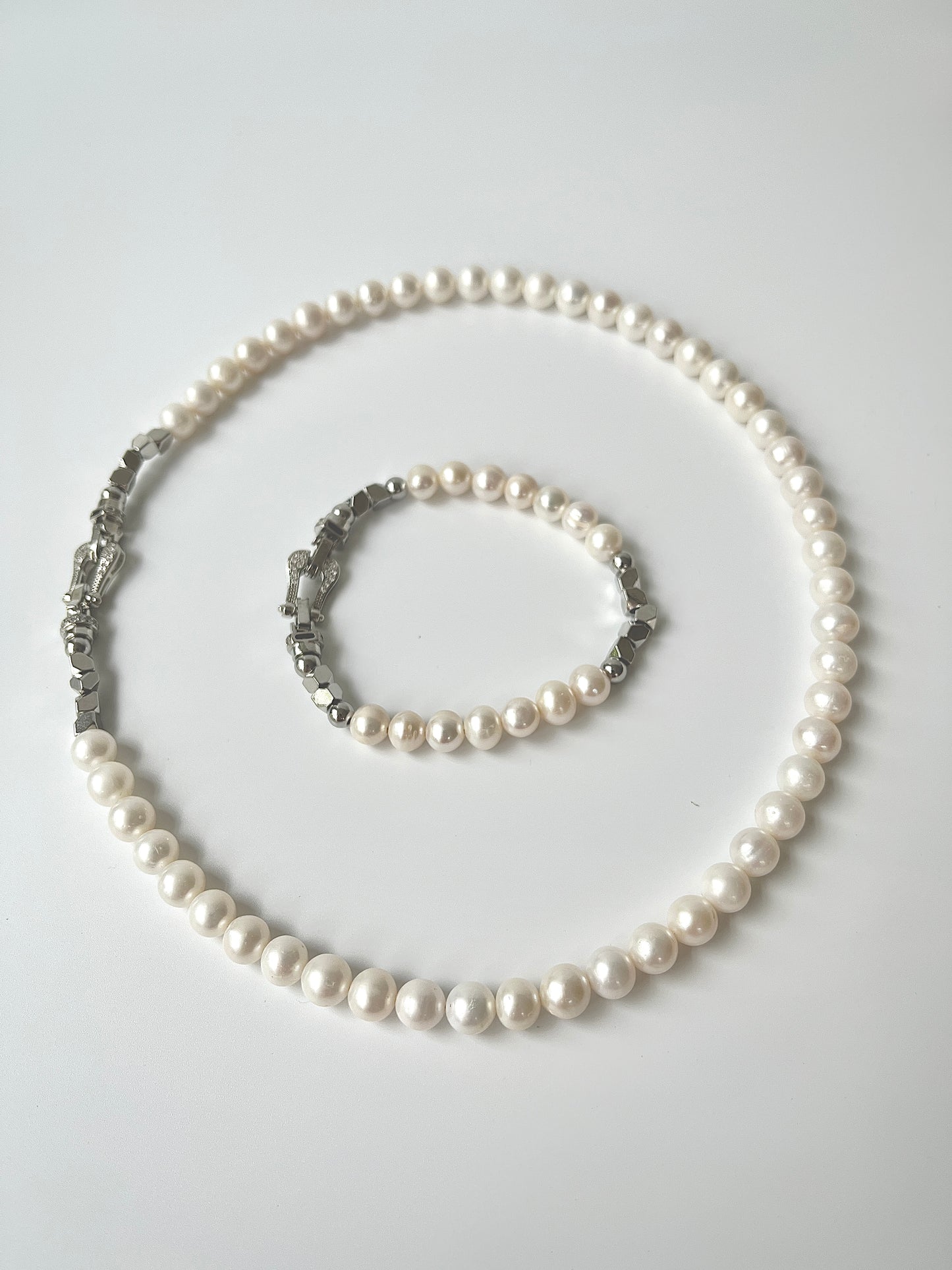 Pearl necklace and bracelet set on a light gray background
