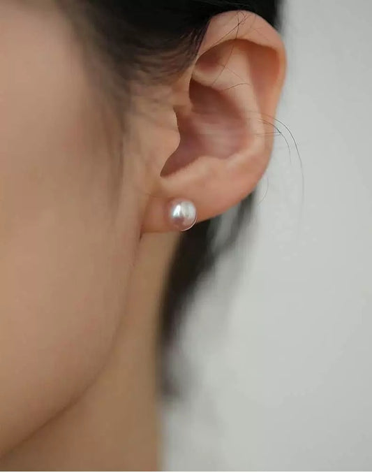 Close-up of an ear wearing a pearl earring with a blurred background