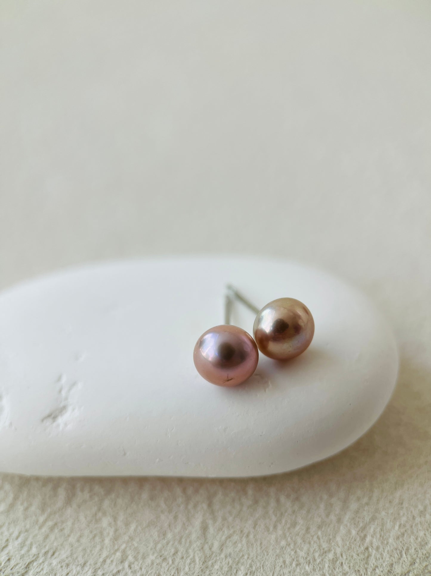 Pair of pearl earrings on a white stone with a neutral background