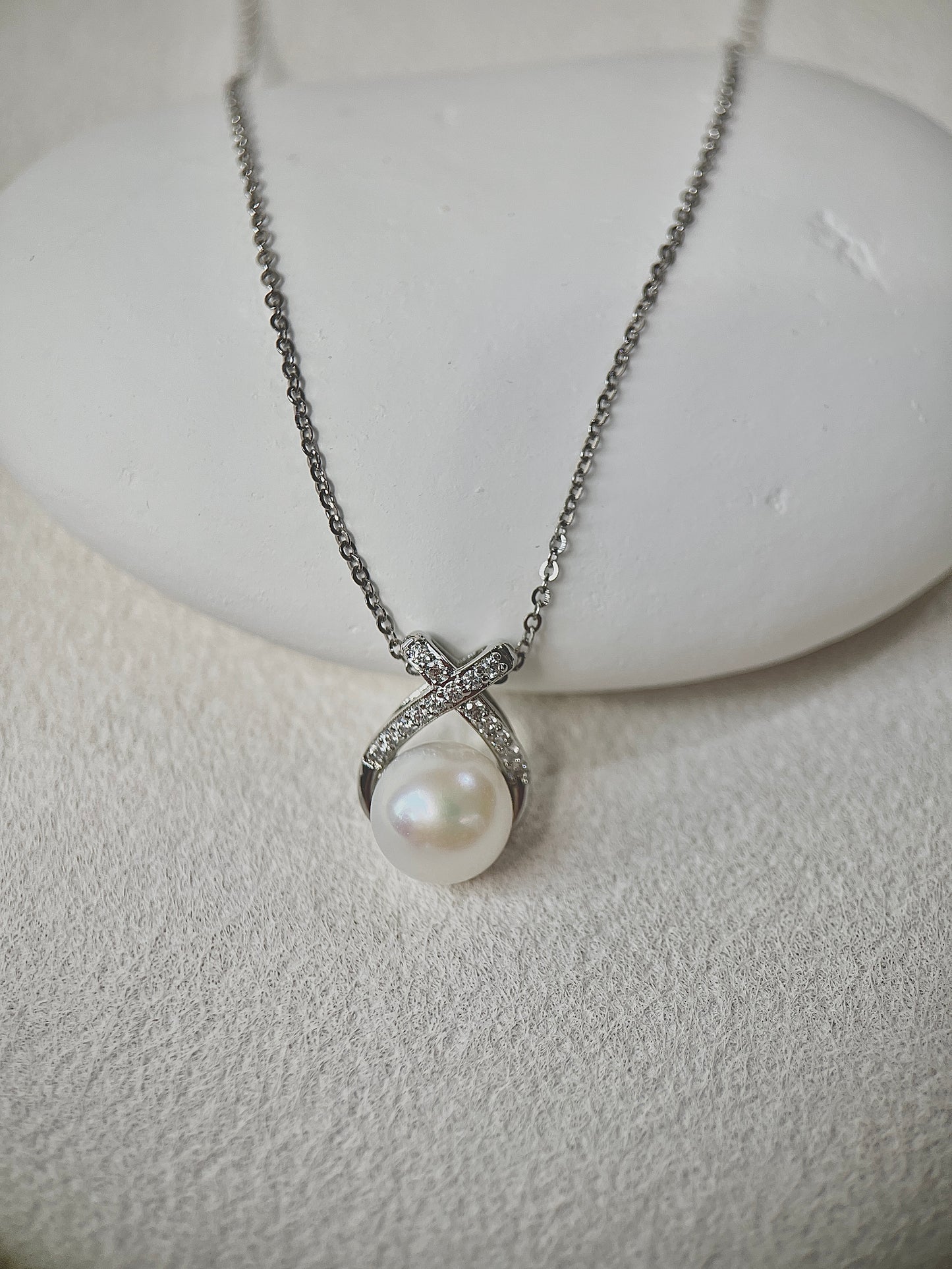 Pearl necklace with silver chain on a white stone surface