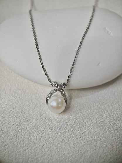 Pearl necklace with silver chain on a white stone surface