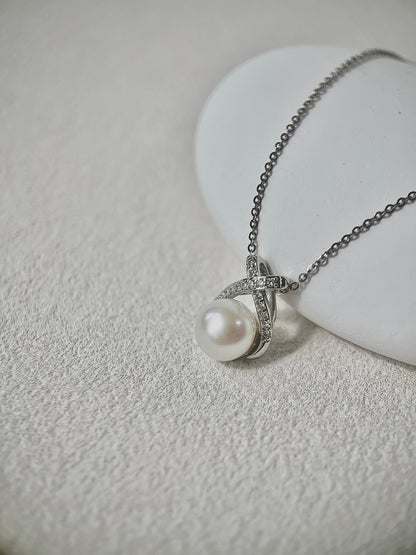 Pearl necklace with silver chain on a textured white surface