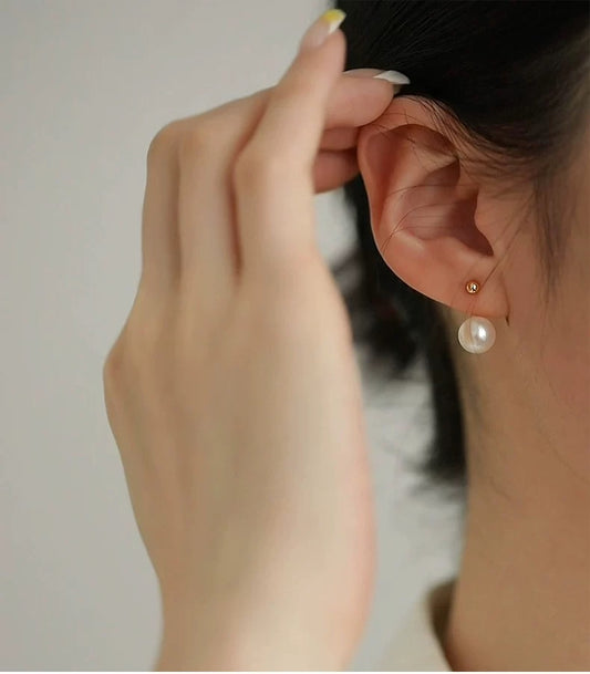 Person wearing a pearl earring with a blurred background