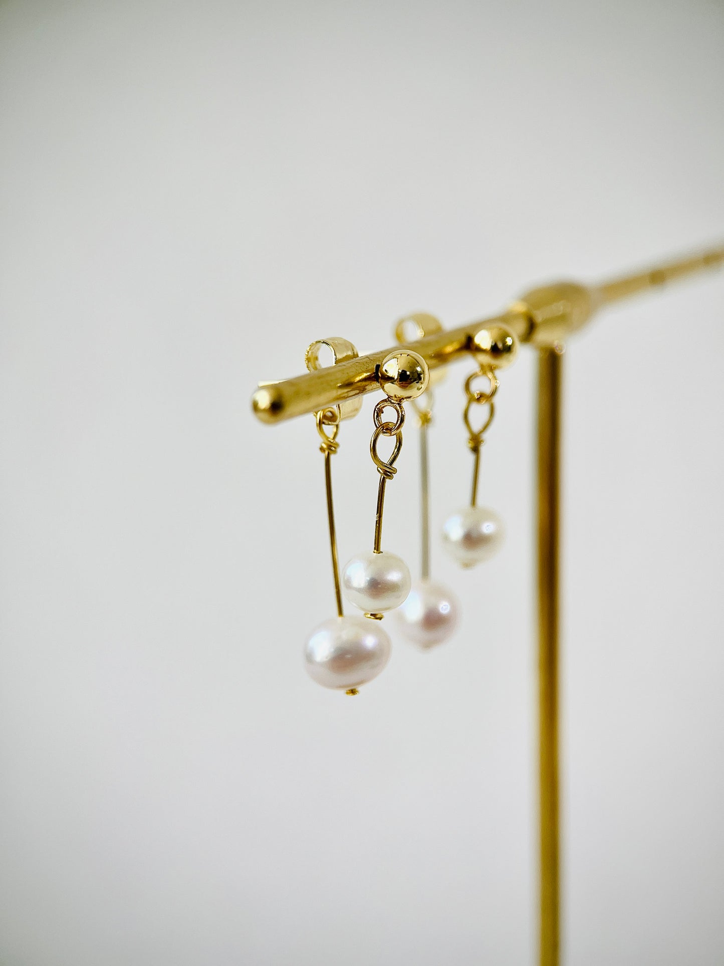 Gold earring with pearl drops on a white background