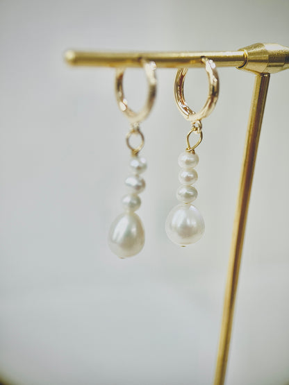 Pearl earrings on a gold stand against a neutral background