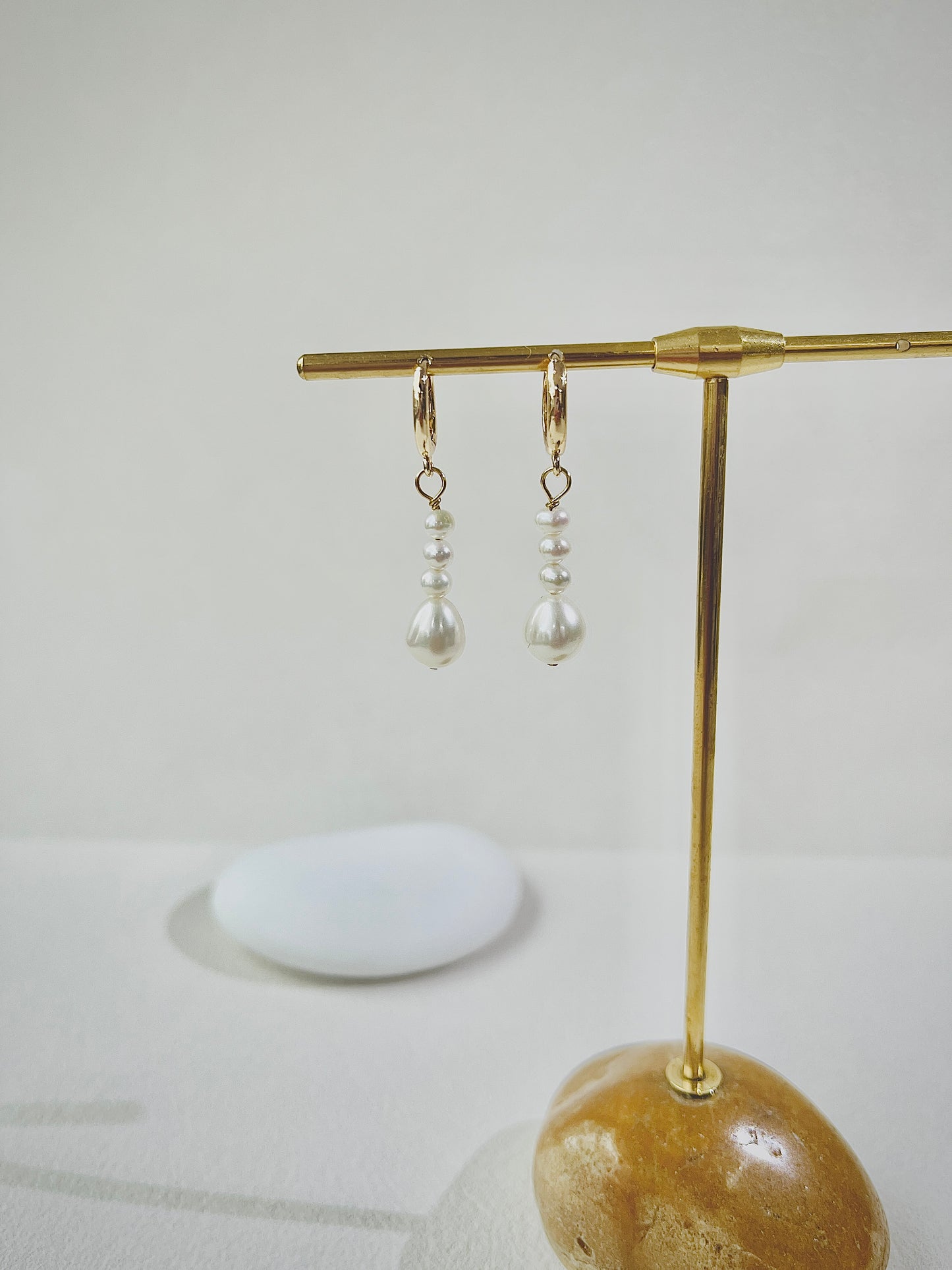 Pair of pearl earrings on a gold stand with a white background