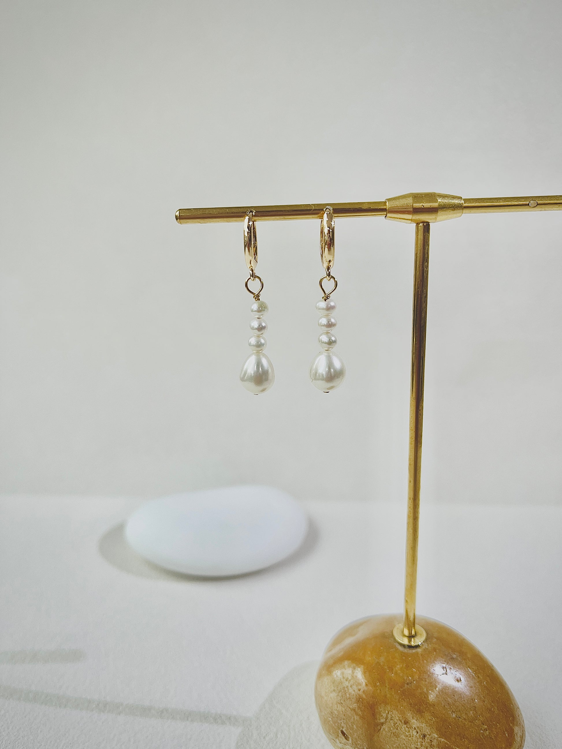 Pair of pearl earrings on a gold stand with a white background