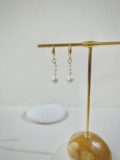 Pair of pearl earrings on a gold stand with a white background