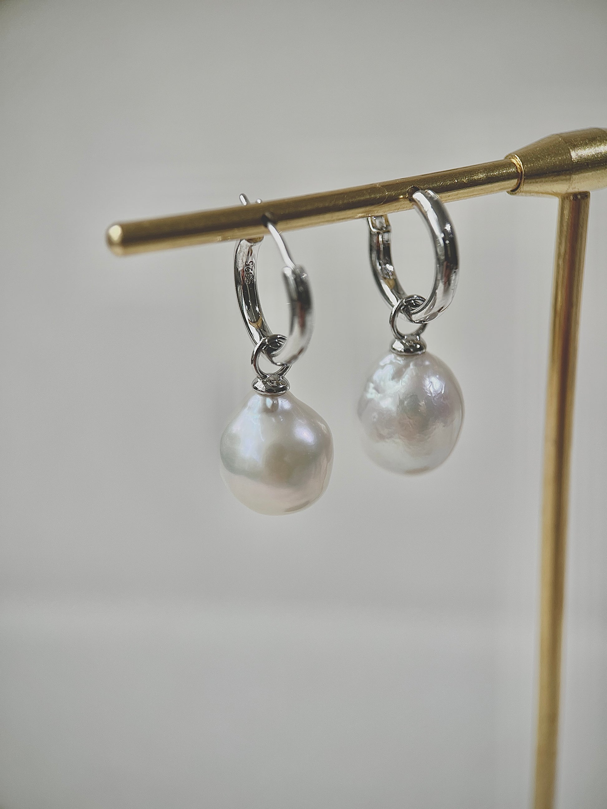 Pearl earrings on a gold stand against a light background