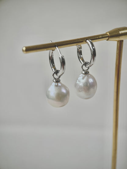 Pearl earrings on a gold stand against a light background