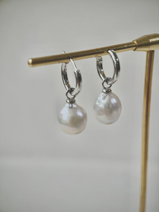 Pearl earrings on a gold stand against a light background