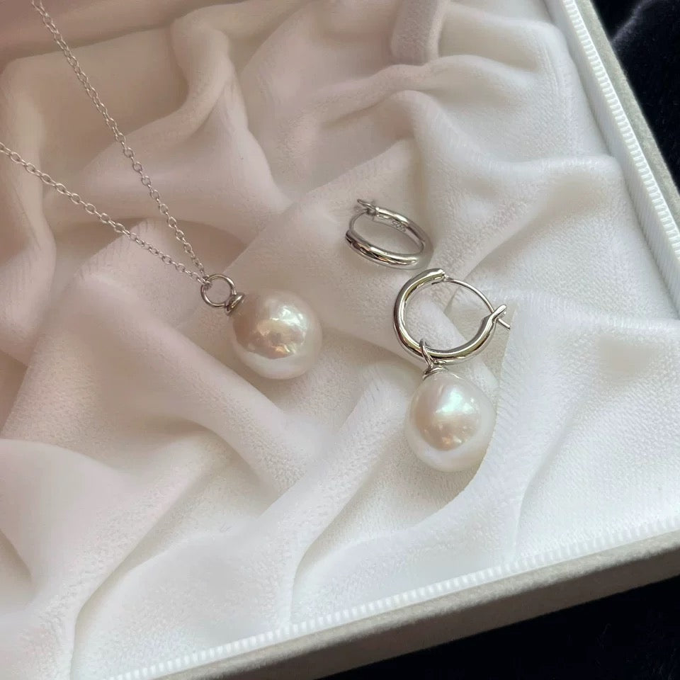 Pearl necklace and earrings on a white fabric surface