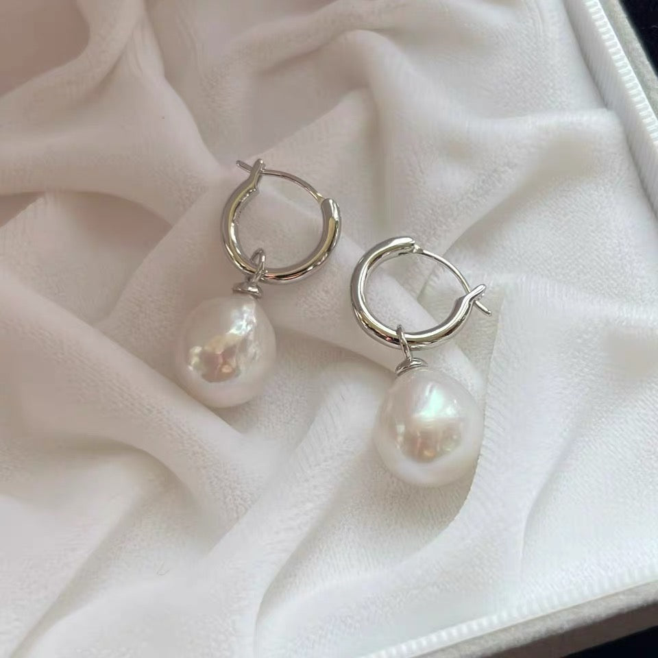 Pearl earrings on a soft white fabric background