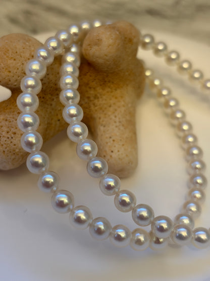 Pearl necklace draped over a textured beige object with a blurred background