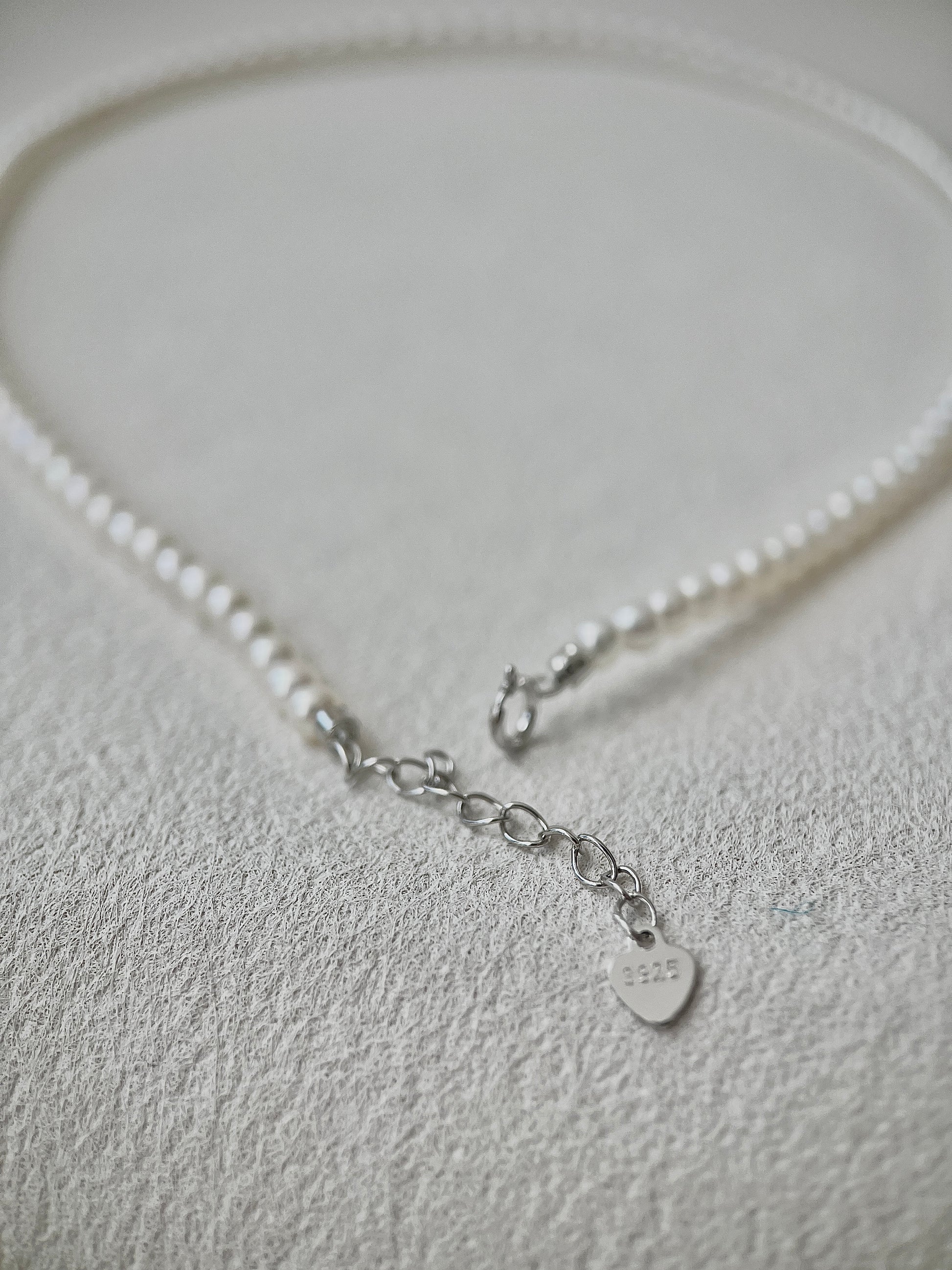 Pearl necklace with a silver clasp on a light gray background