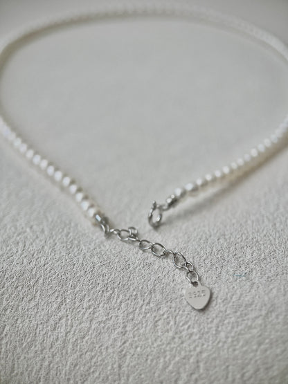 Pearl necklace with a silver clasp on a light gray background
