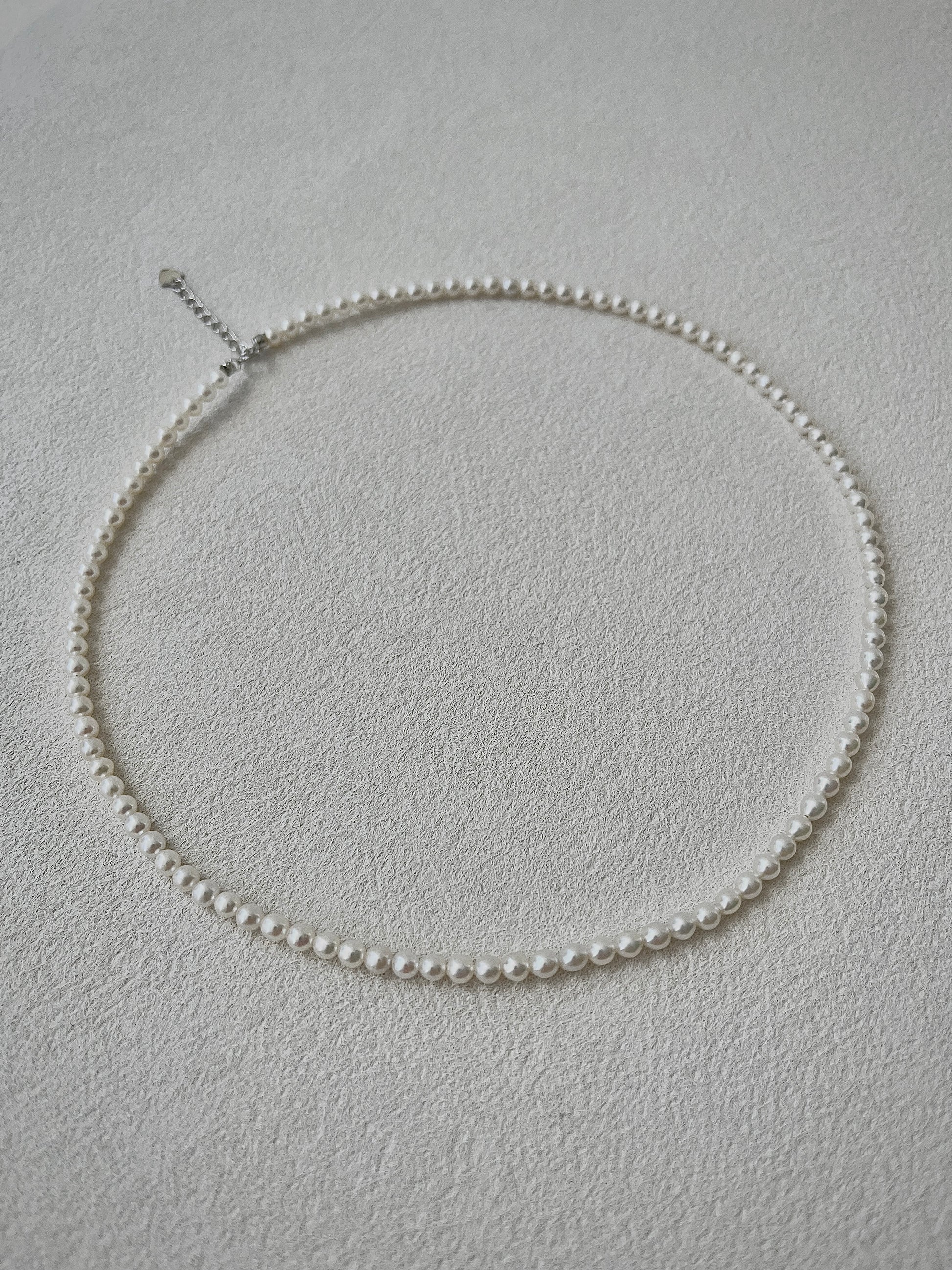 white Pearl necklace on a light gray background