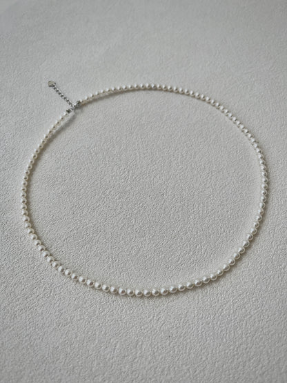 white Pearl necklace on a light gray background