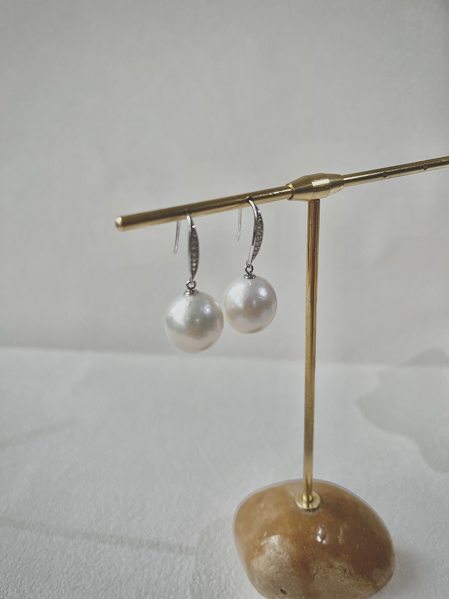 Pearl earrings on a gold stand with a stone base against a light background