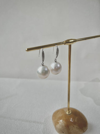 Pearl earrings on a gold stand with a stone base against a light background
