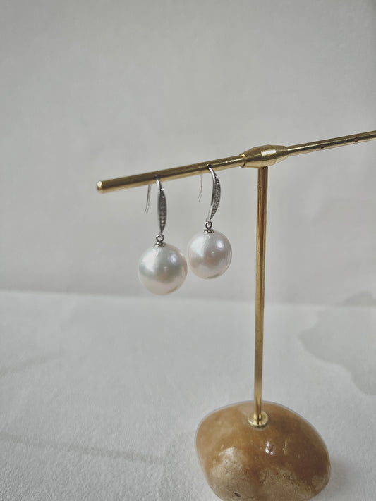 Pearl earrings on a gold stand with a stone base against a light background
