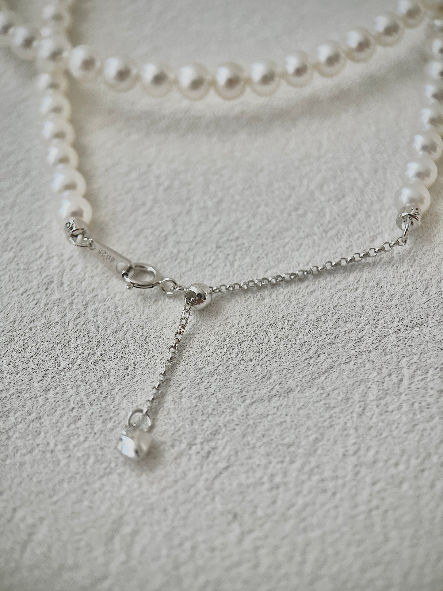 Pearl necklace with silver clasp on a light gray background