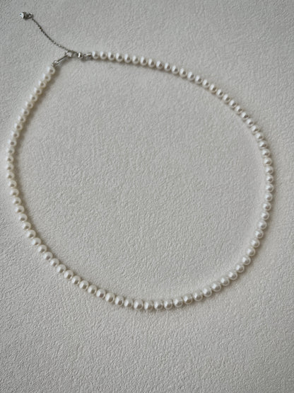 Pearl necklace on a light gray background