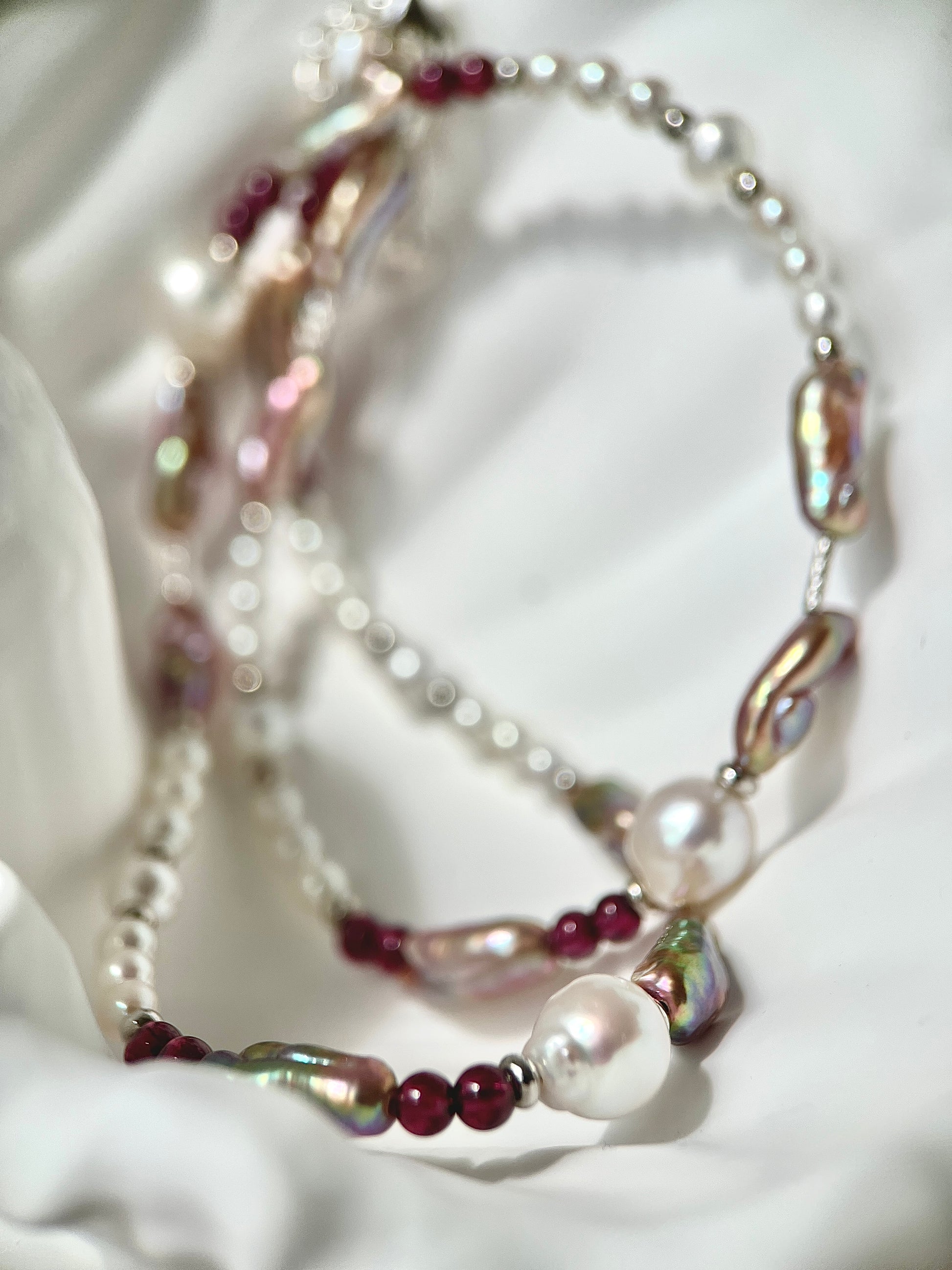 Necklace with mixed pearls and red beads on a textured white surface