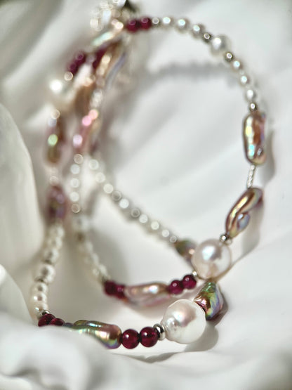 Necklace with mixed pearls and red beads on a textured white surface
