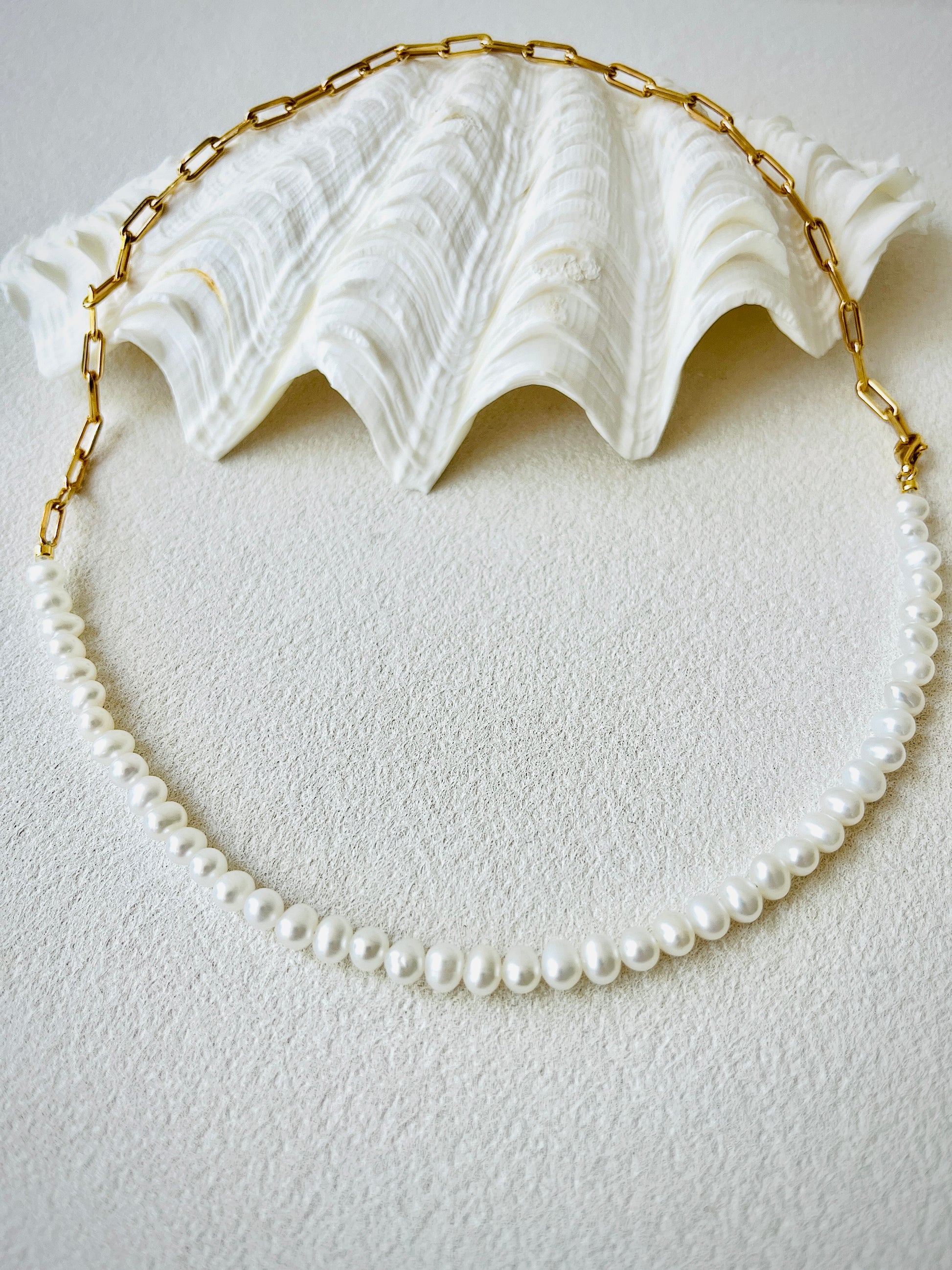 Gold pearl necklace on a white surface