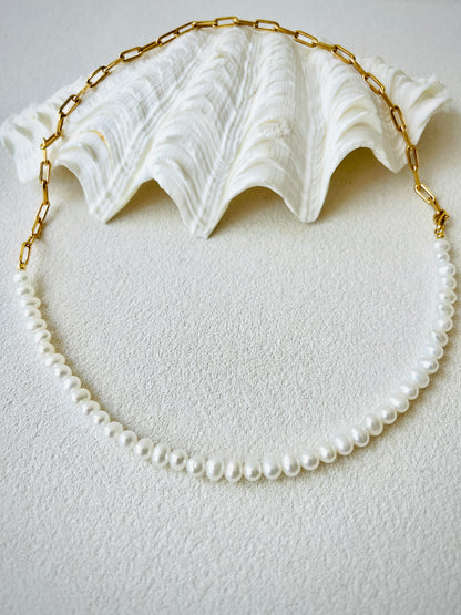 Gold pearl necklace on a white surface