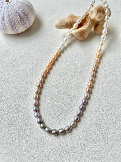Pearl necklace with coral and shell on a light background