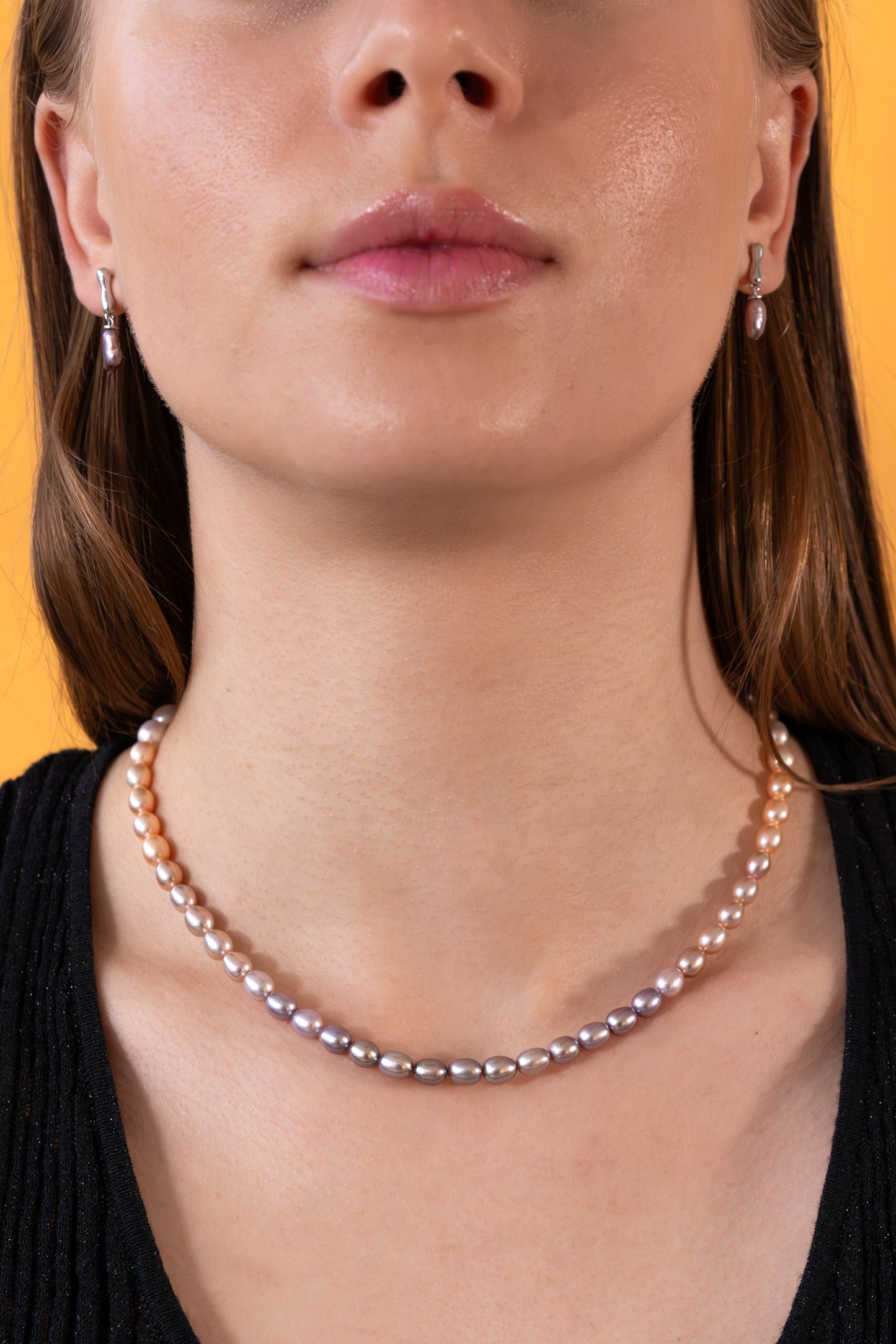 Woman wearing a rainbow pearl necklace with a blurred background