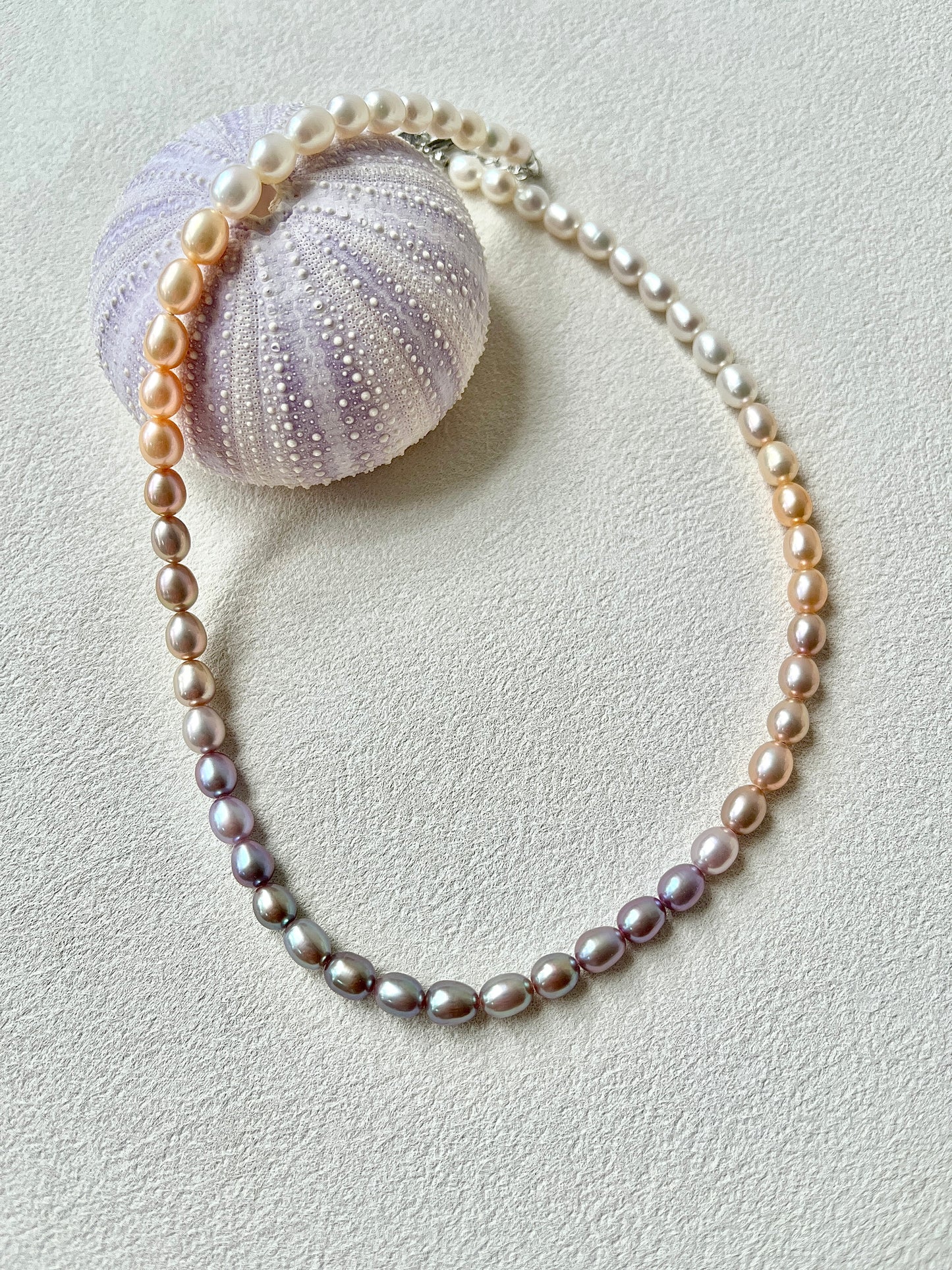 Pearl necklace with a purple sea urchin on a light gray background