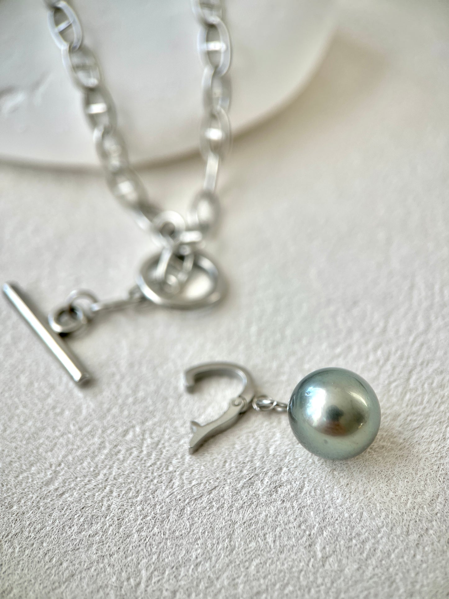 Silver necklace with a pearl pendant on a light background