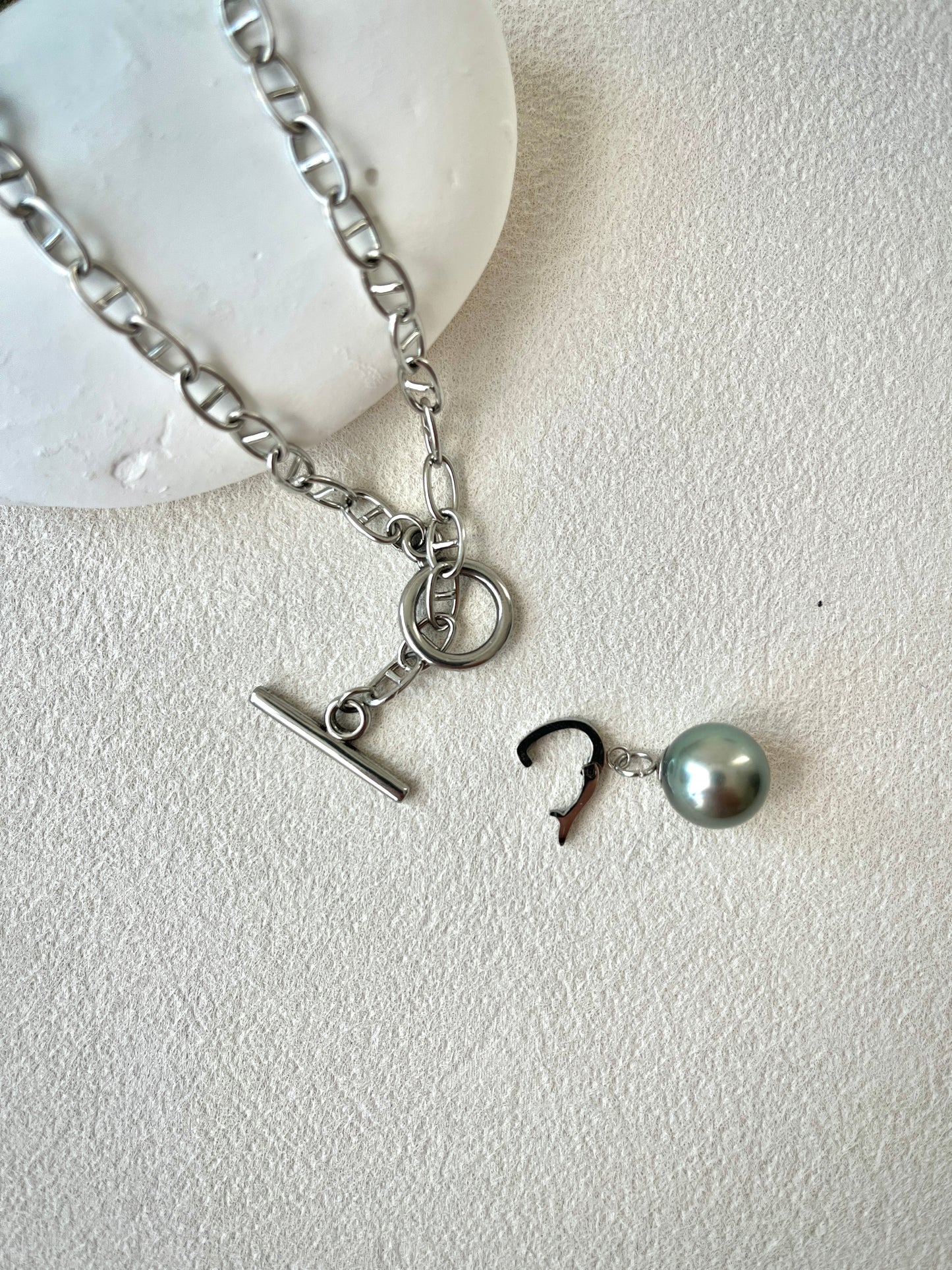 Silver necklace with charms on a white background, adjustable pendant.
