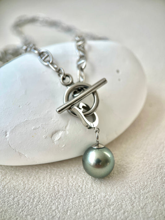 Silver necklace with a single pearl pendant on a white stone background
