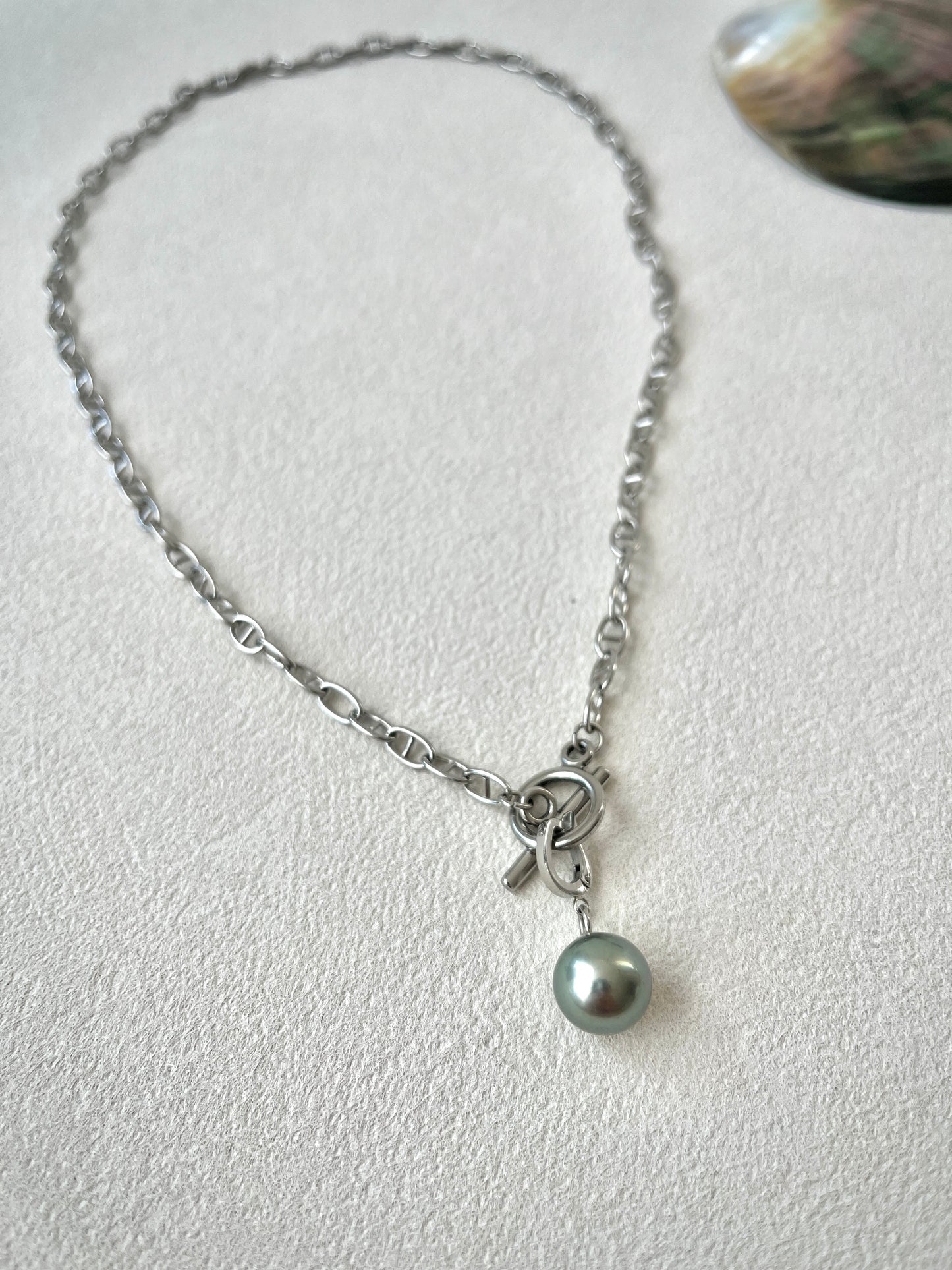 Necklace with a single pearl pendant on a light gray background